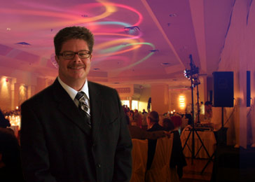 Image for About Us page showing Drew in a suit with a sophisticated party in the background.