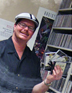 Radio personality Drew Miller shown choosing music for his show at the station